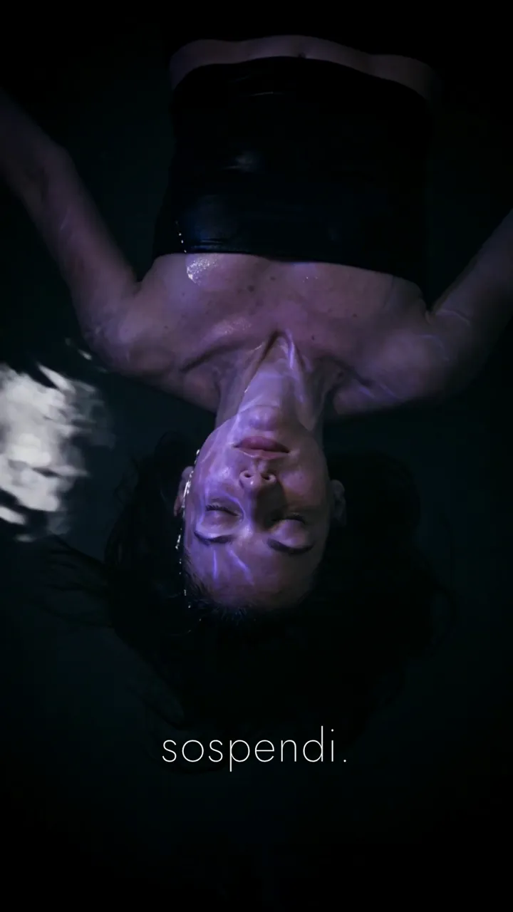Fotogramma dello spot: una donna che galleggia al buio e la scritta sospendi