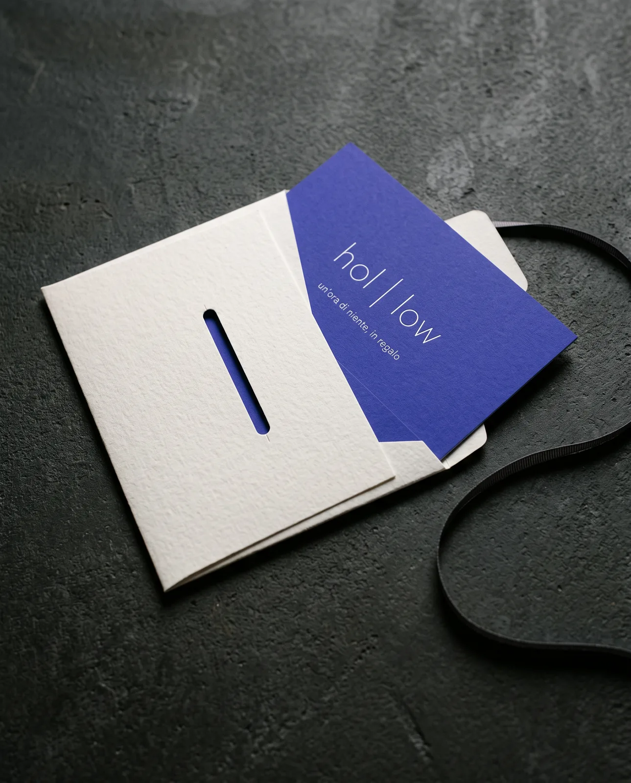 Una gift card indaco che esce da una busta con una fessura fustellata
