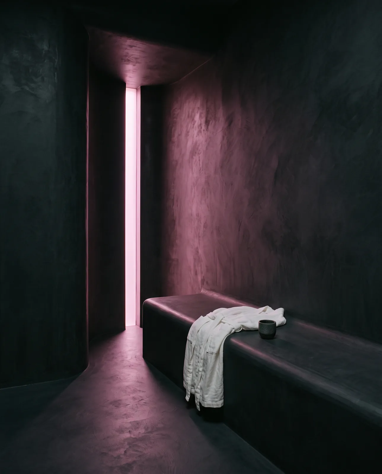 La stanza del ritorno: una panca di cemento e una fessura di luce magenta
