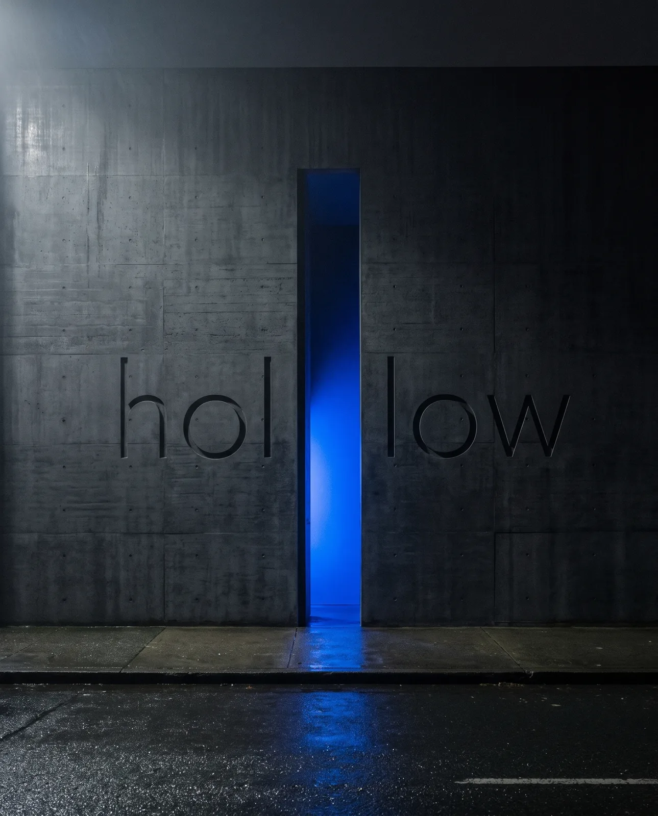 La facciata di Hollow: un muro di cemento con il nome inciso e una fessura di luce blu al posto della porta