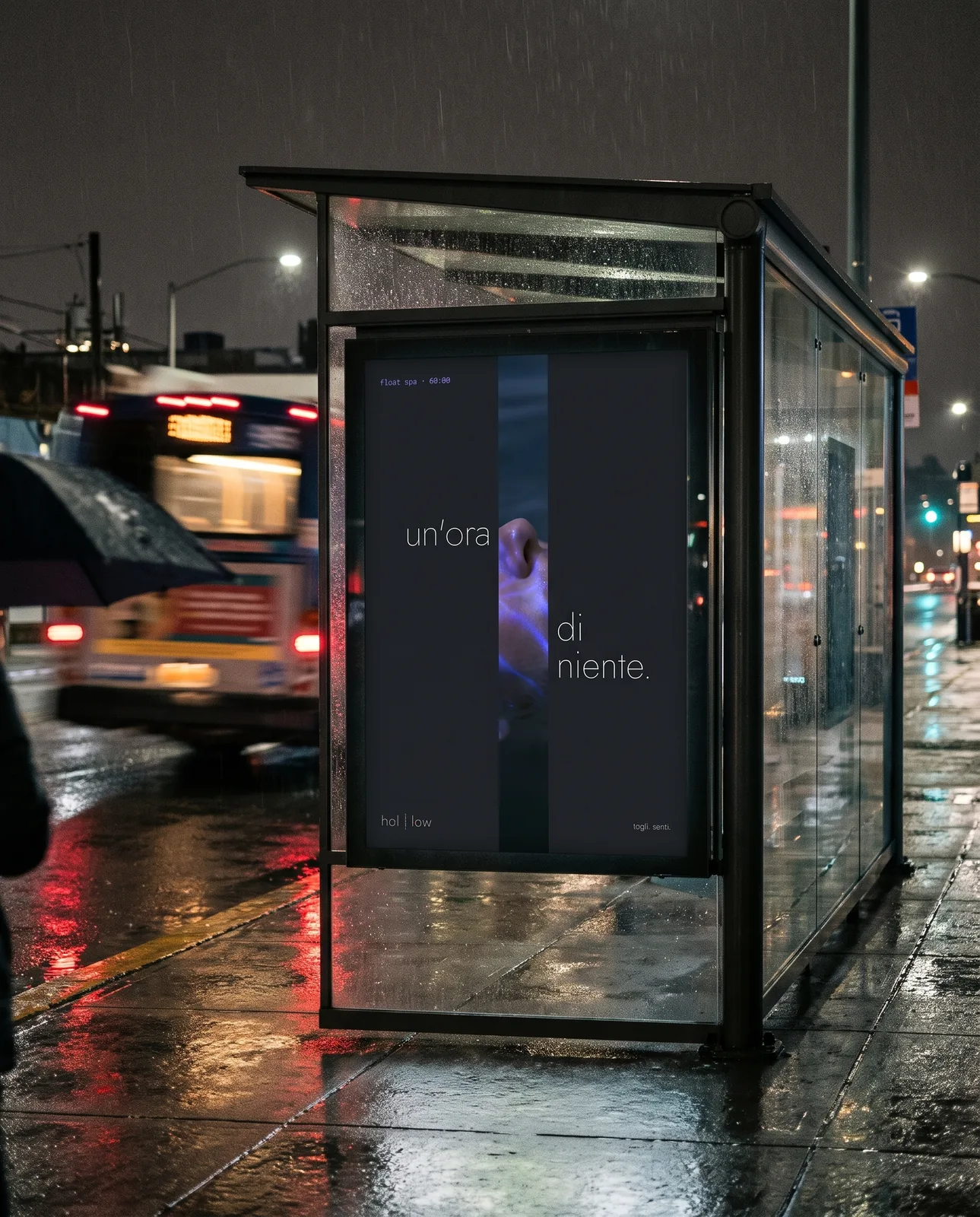 Una pensilina dell'autobus di notte sotto la pioggia, con il poster retroilluminato di Hollow